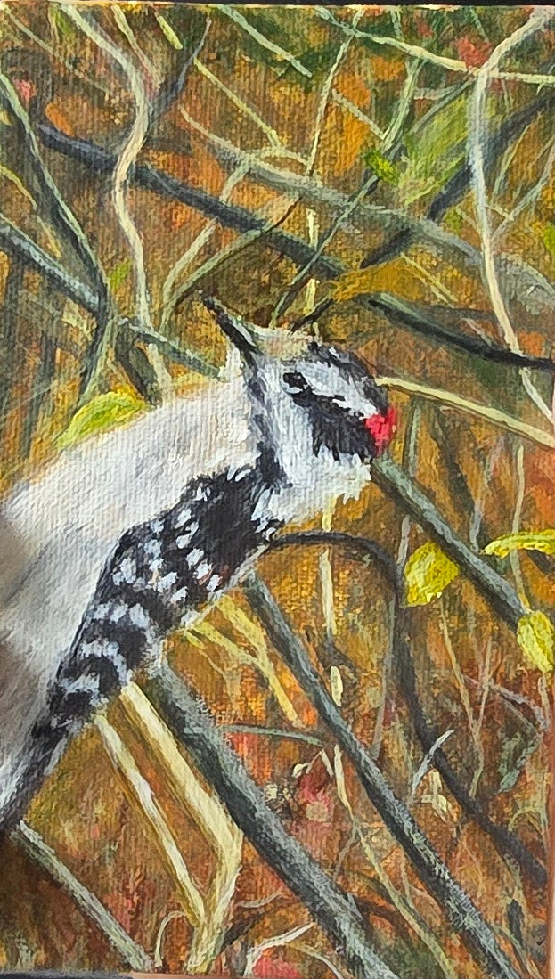 Hand holding a small rectangular painting of a bird on a textured surface.