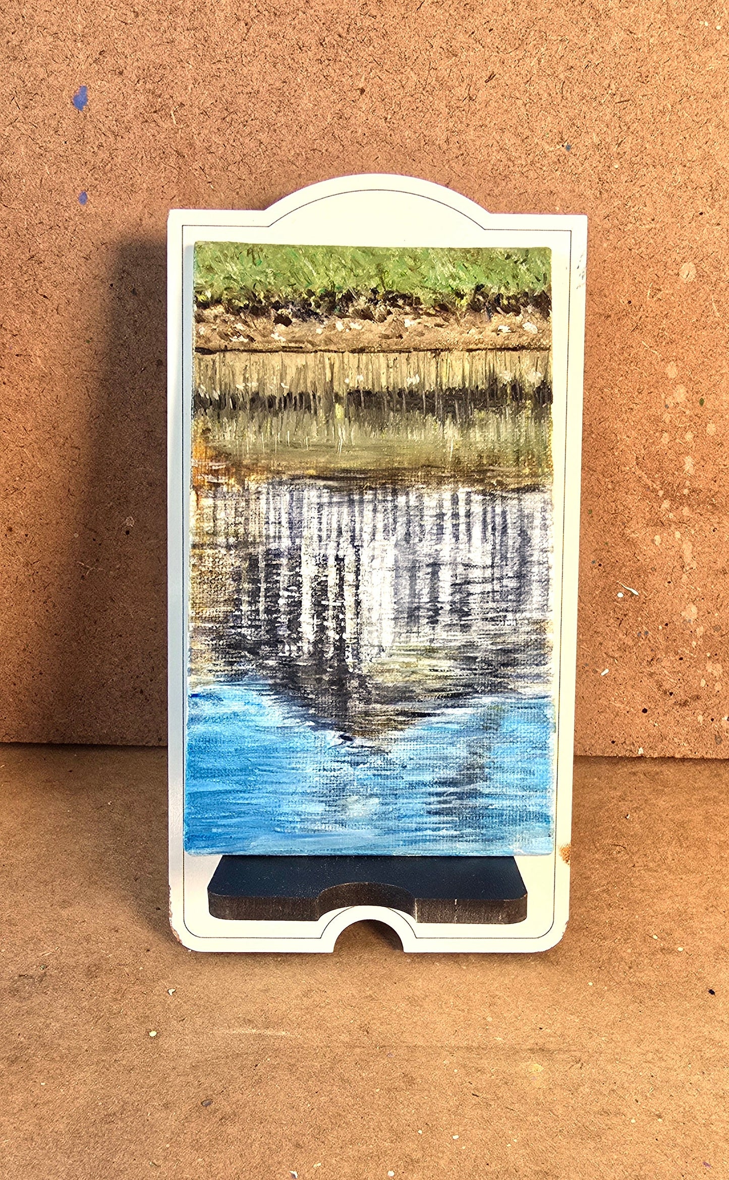 Card with a scenic reflection of trees and water on a brown surface