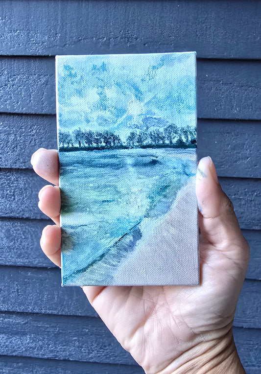 Hand holding a textured blue and green card against a dark background