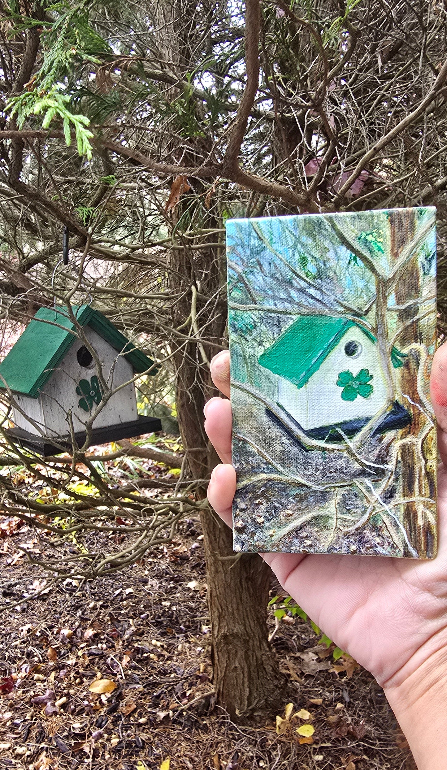 Hand holding a small rectangular card with a green clover design against a natural background.