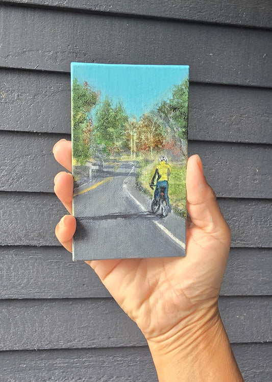 Hand holding a small postcard with a scenic view on a textured gray surface