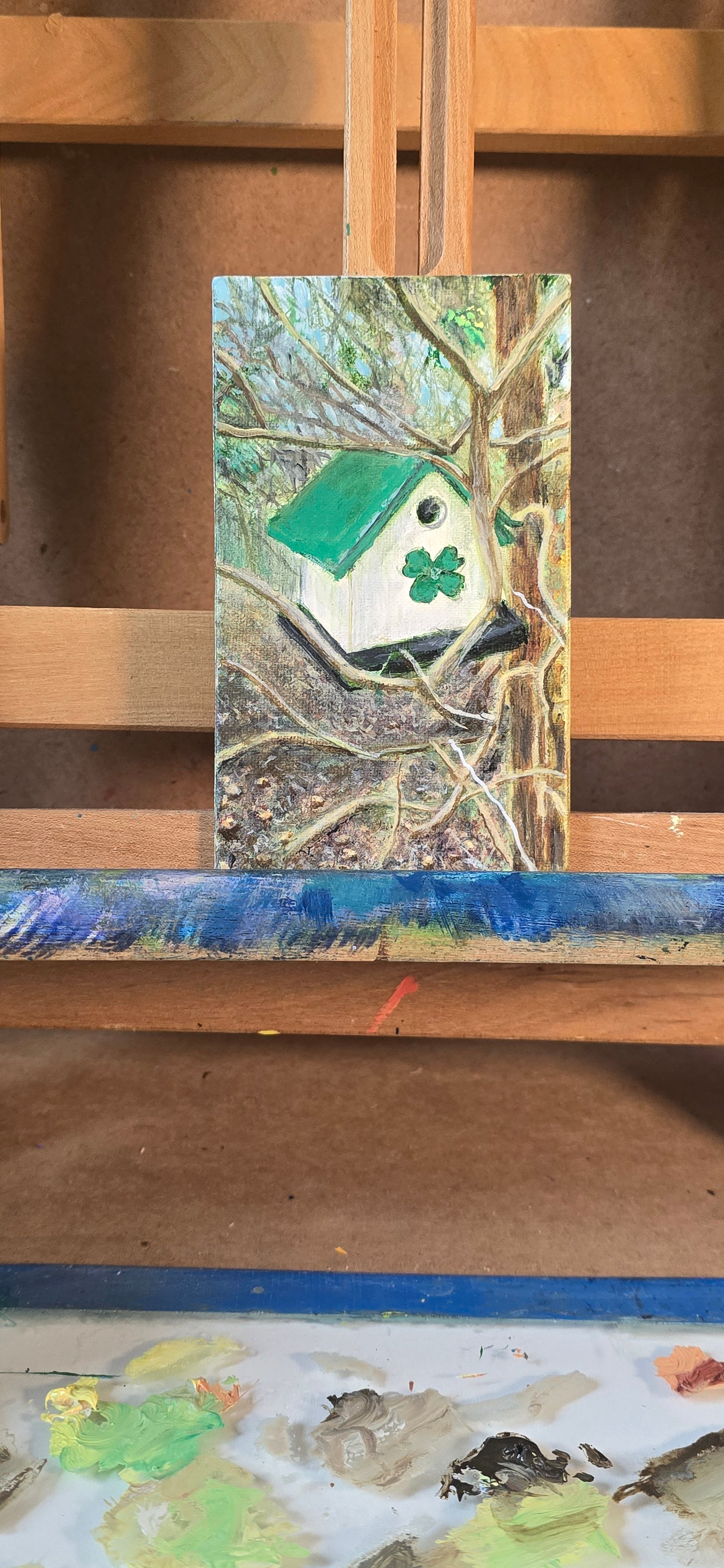 Artistic depiction of a bird house with a four-leaf clover on a textured surface.