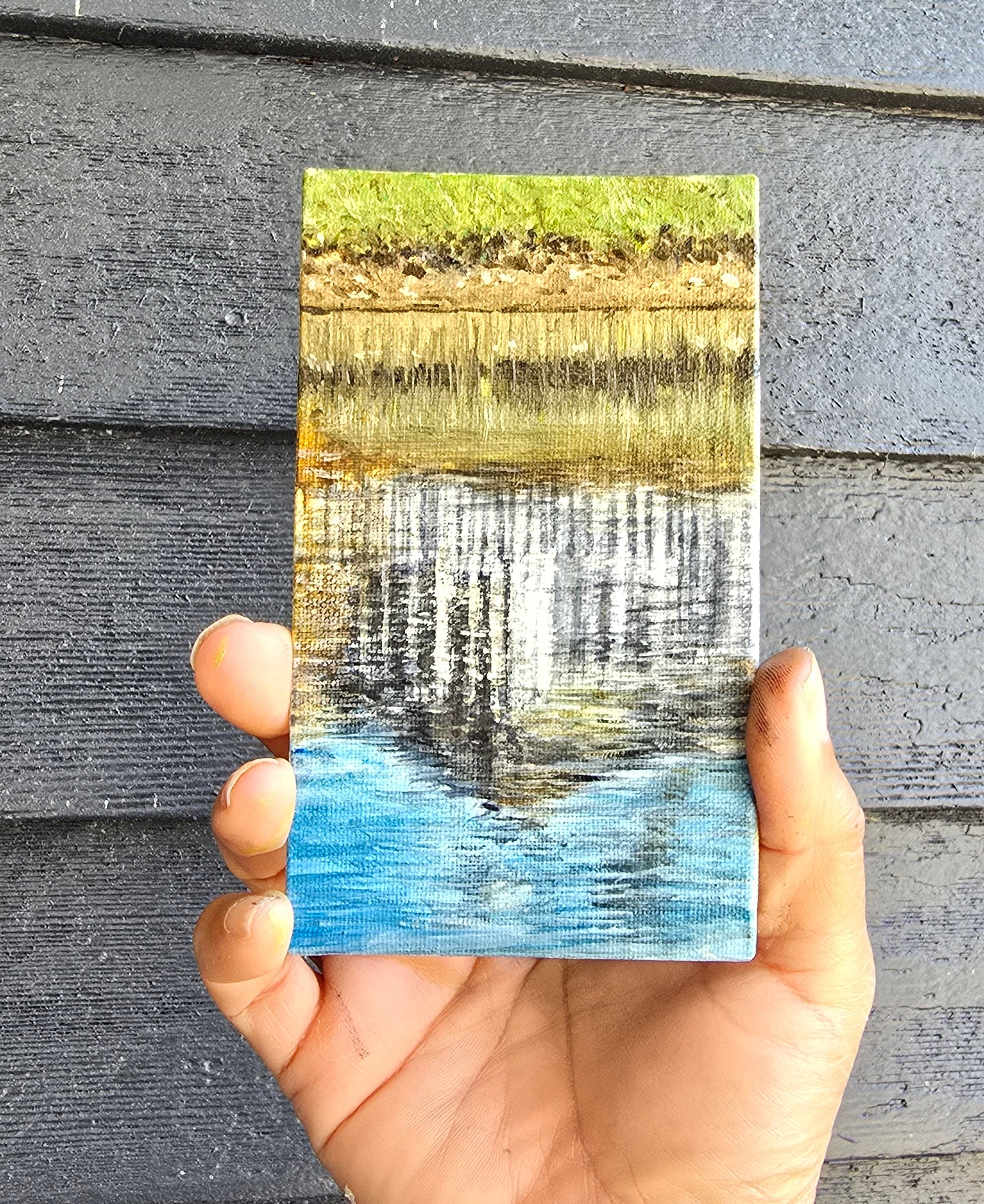 a tiny painting of water reflections of a building in greens and blues
