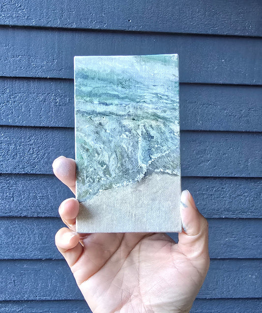 Hand holding a rectangular stone sample against a blue textured background