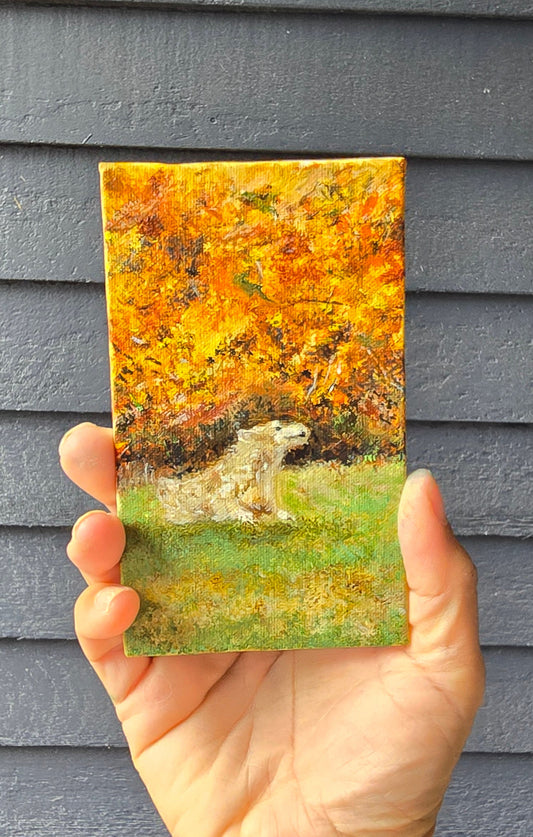 Hand holding a rectangular piece of paper with a nature-themed design against a gray textured background